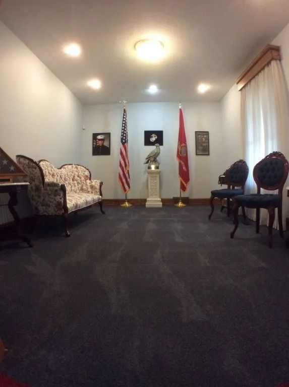 Small meeting room with chairs, flags, and a podium against a white wall
