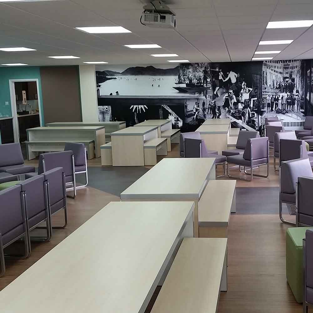 Empty modern office lounge with tables, chairs, and a black-and-white mural wall