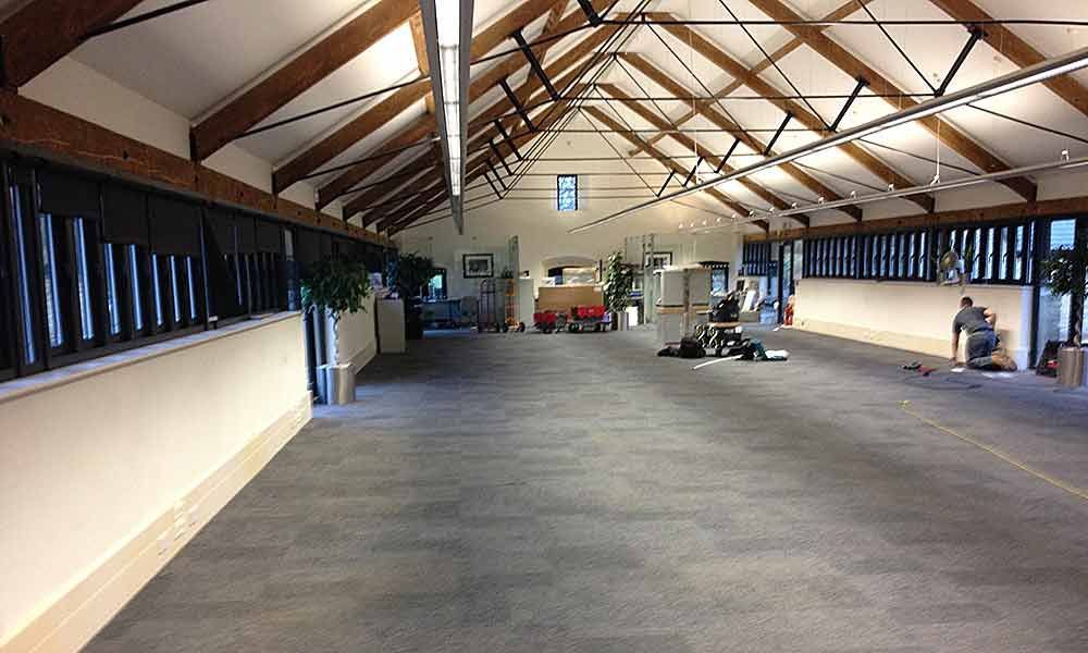 Spacious attic-like hall with exposed wooden beams, skylights, and a few items scattered on the floor