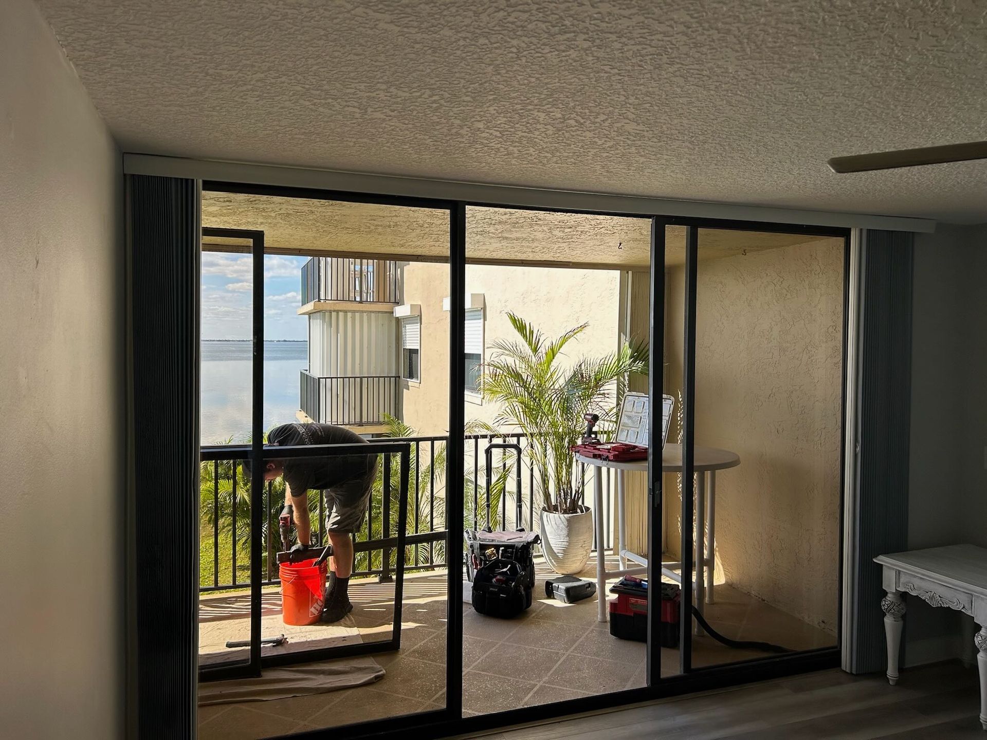 A florida sliding glass door repair technician repairing a sliding glass door on a balcony