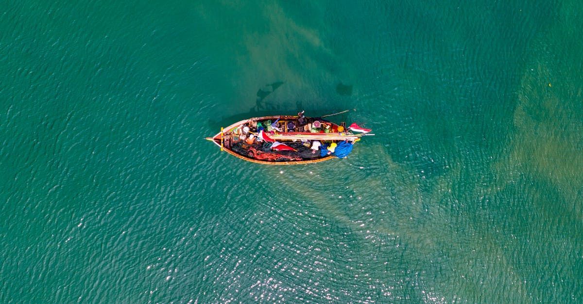Boat on turquoise water, viewed from above, carrying people and goods on a luxury vacation.