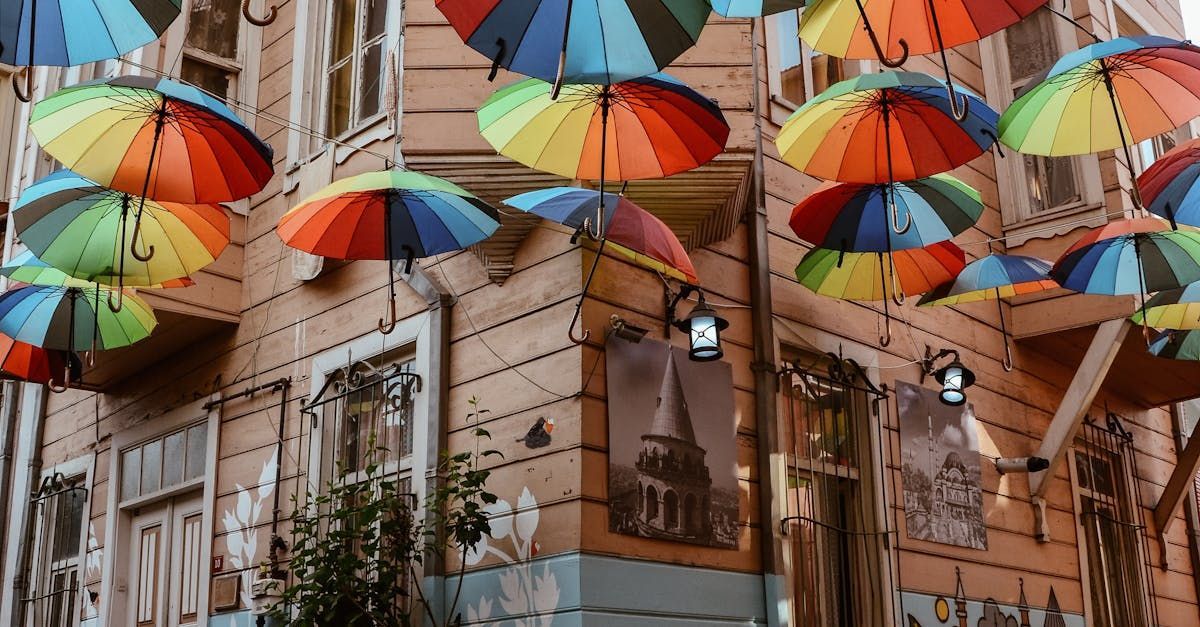 Rainbow umbrellas suspended over an old building, creating a vibrant, colorful street scene in Europe.