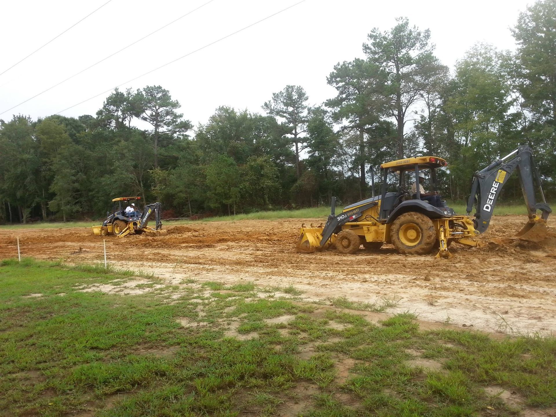 Two tractors are working on a dirt field.
