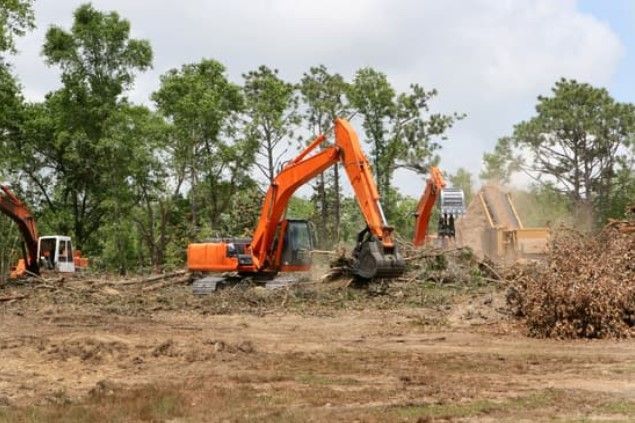 A couple of excavators are working on a dirt field.