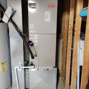 Gray HVAC furnace and water heater in a basement utility area with exposed framing and piping
