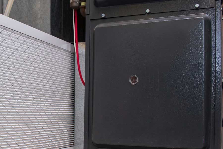 Black wall-mounted box with a red cable beside a patterned gray panel.