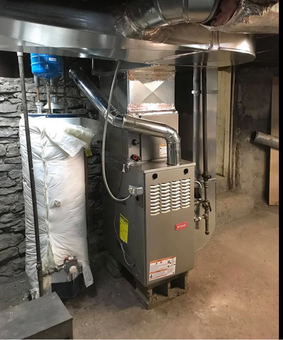 Basement furnace and ductwork beside insulated pipes and a concrete wall