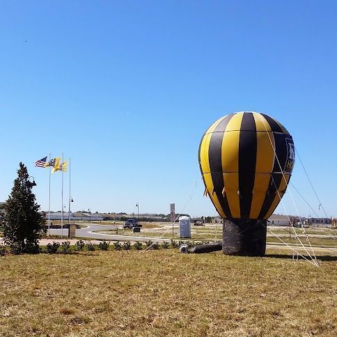 A large yellow and black hot air balloon is sitting in the middle of a grassy field.