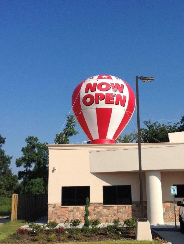 A red and white hot air balloon that says now open