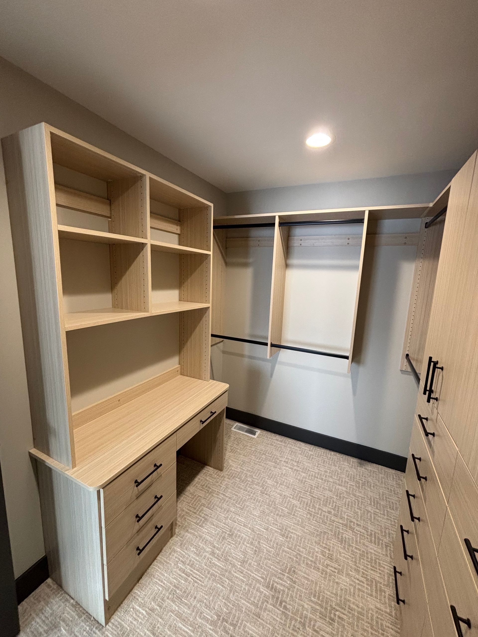 Walk-in closet with built-in wood shelving, drawers, hanging rod, and a window with blinds.