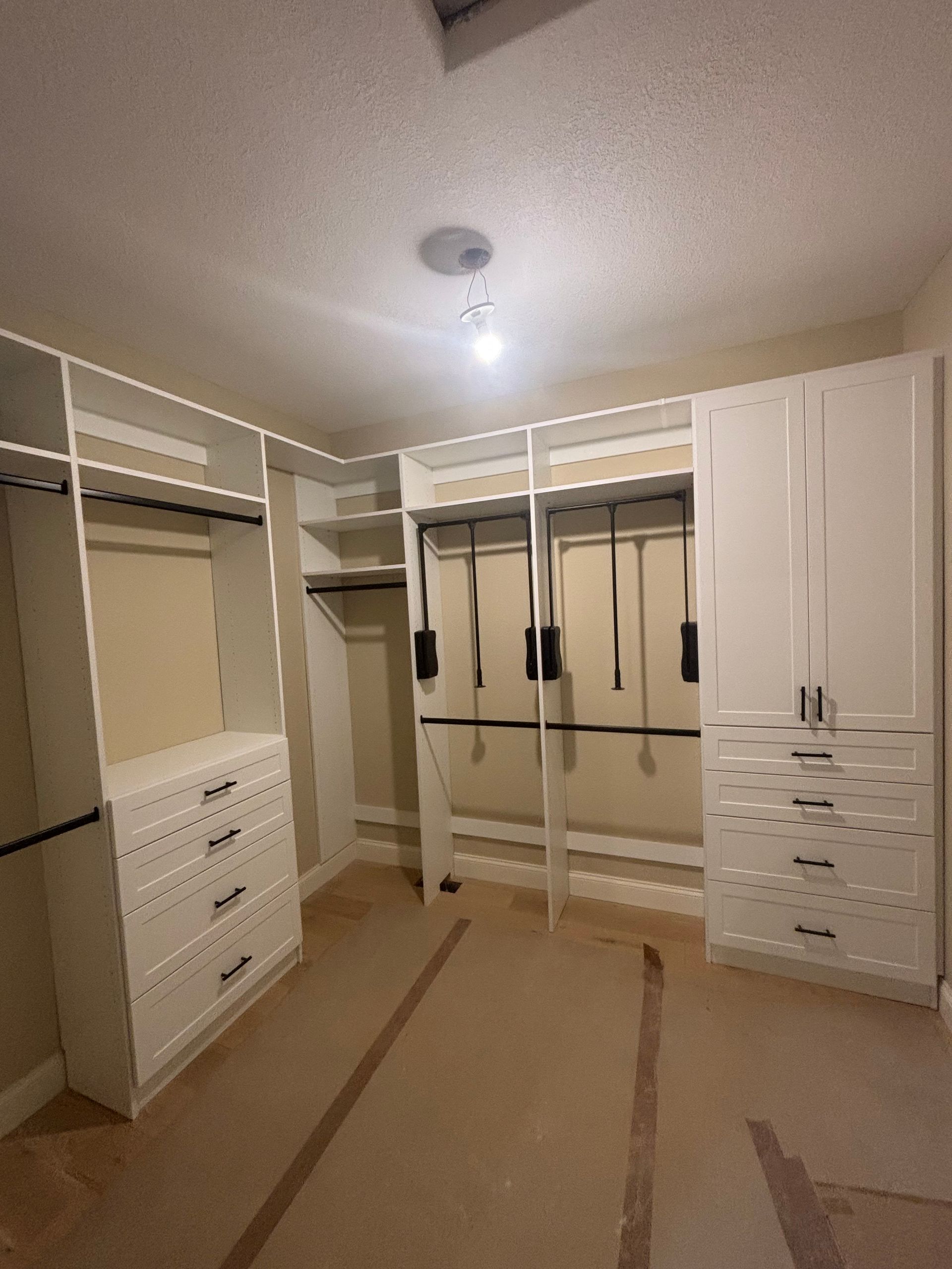 Spacious walk-in closet with white shelves, drawers, hanging rods, and beige carpet.