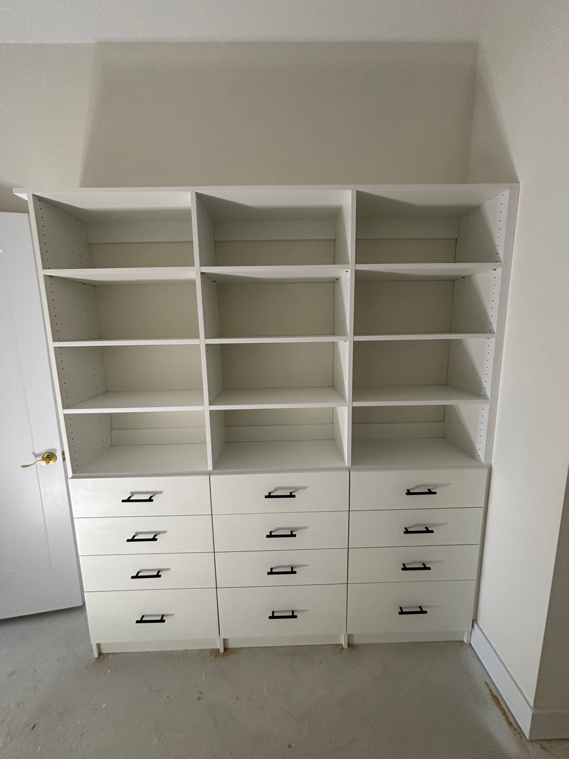 White built-in cabinet with open shelves and drawers in a small room; doors open on both sides.