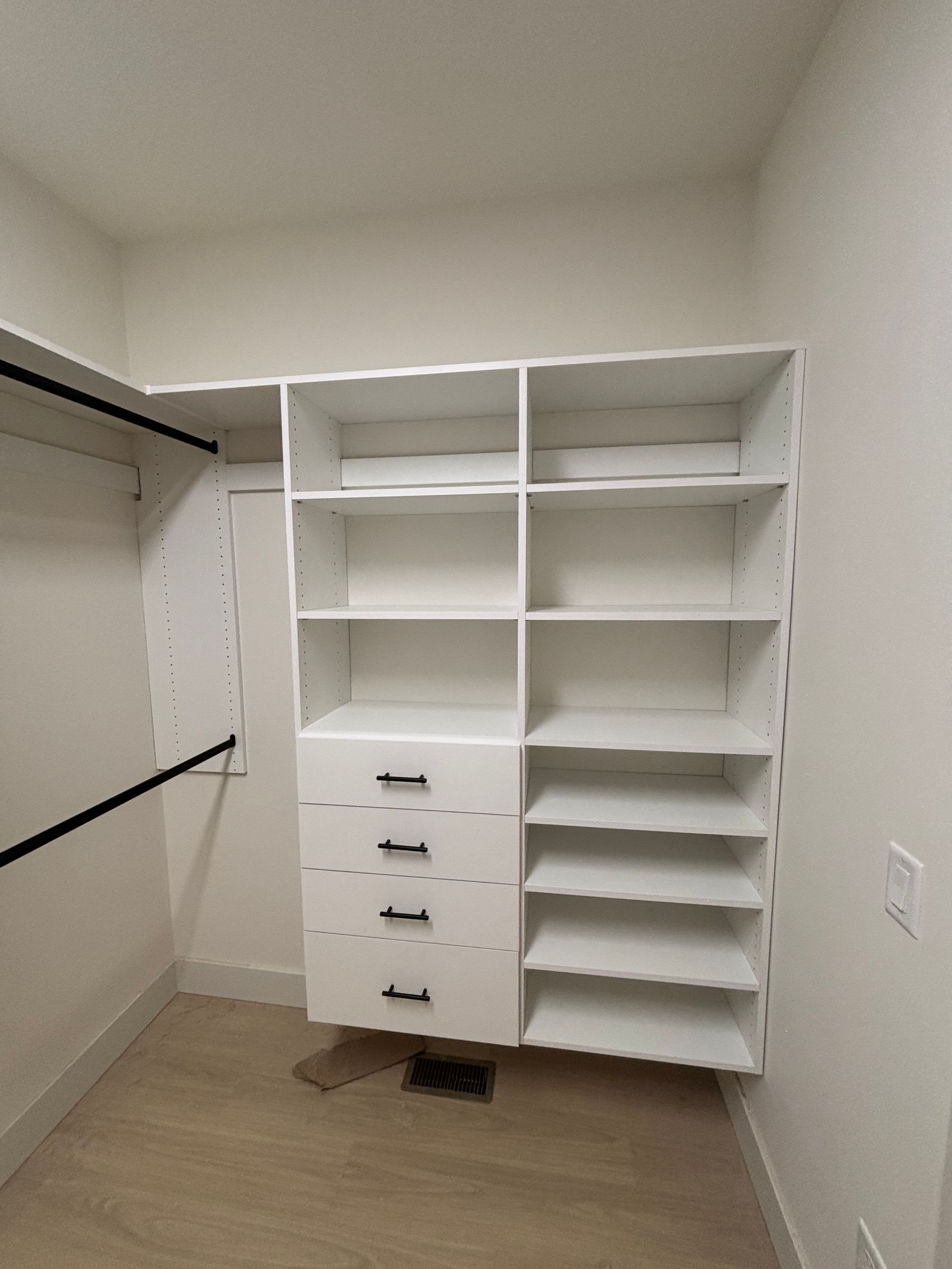 Walk-in closet with white shelving, hanging rod, drawers, and shoe shelves on beige carpet