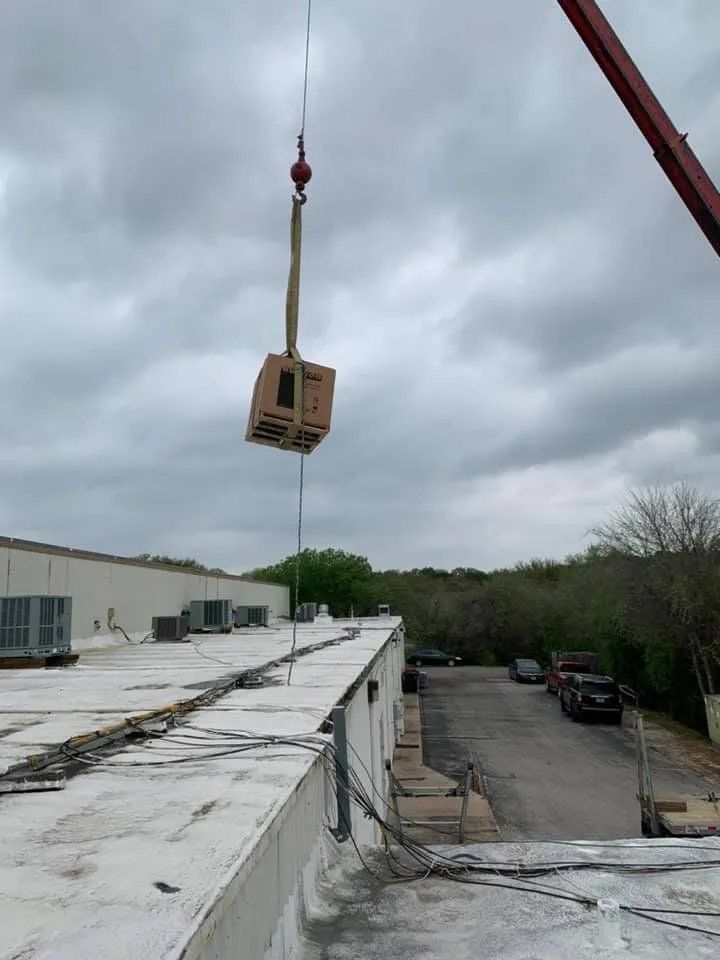 A crane is lifting a box from the roof of a building.