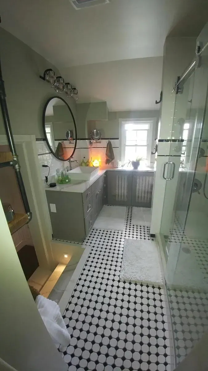 A bathroom with a sink , mirror , and shower.