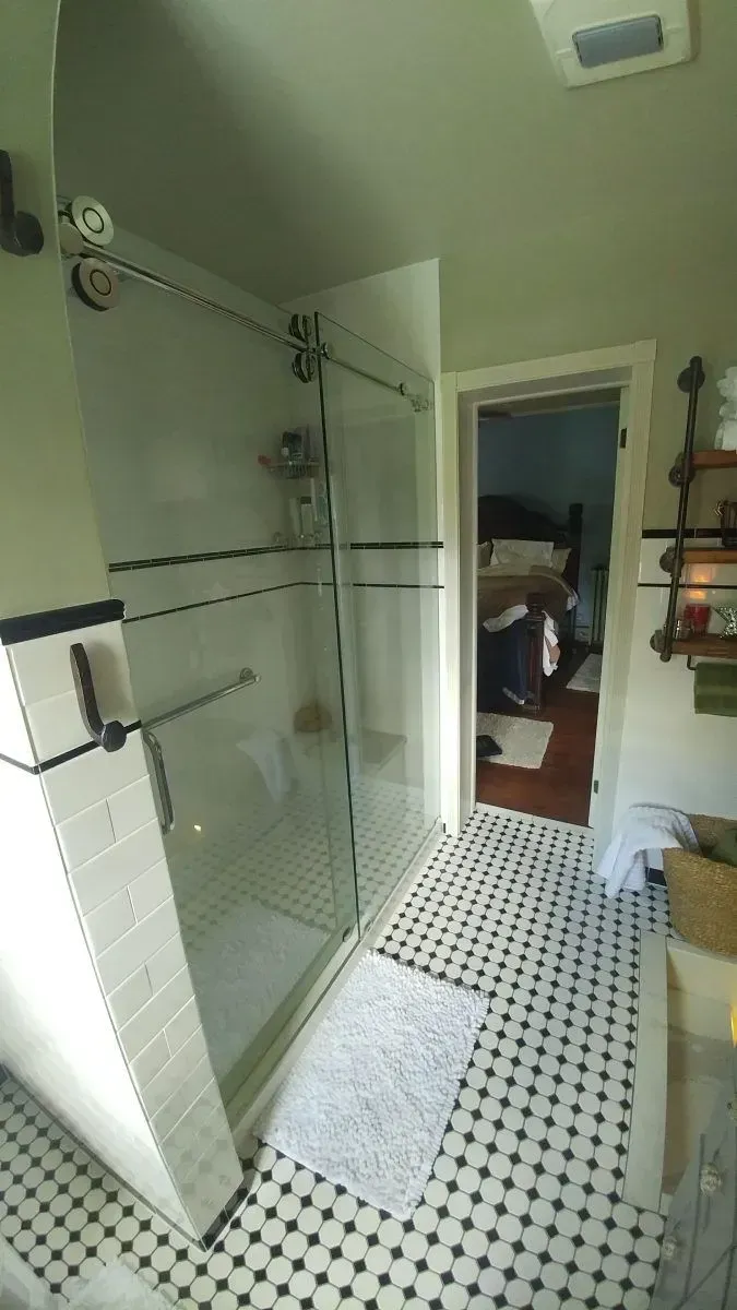 A bathroom with a walk in shower and a black and white tile floor.