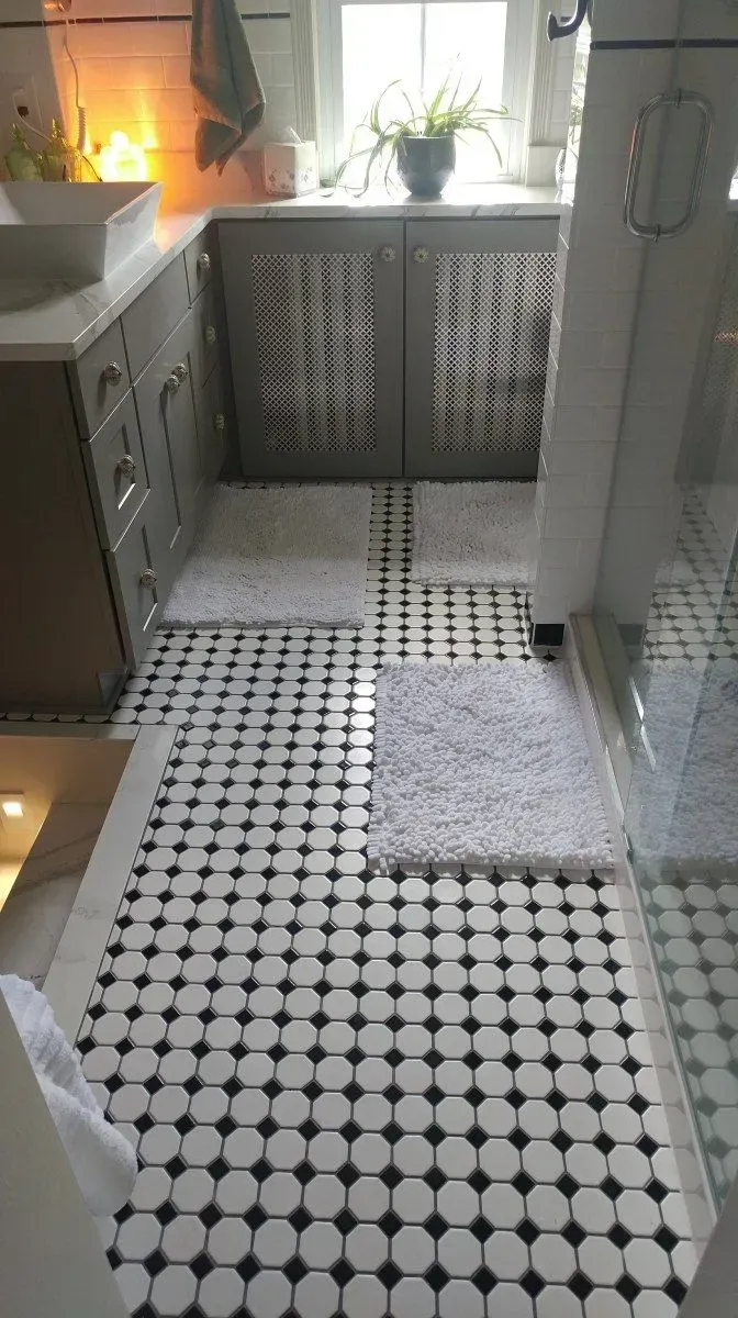 A bathroom with a black and white tile floor and a sink.
