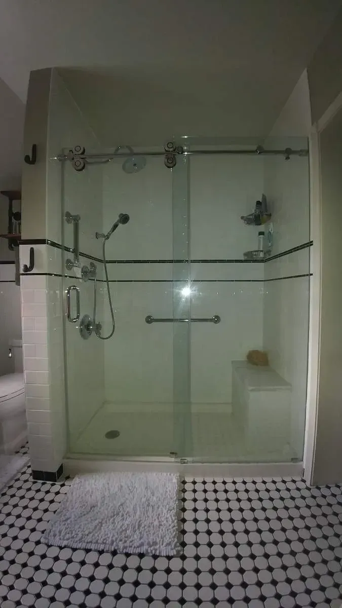 A bathroom with a walk in shower with a sliding glass door.