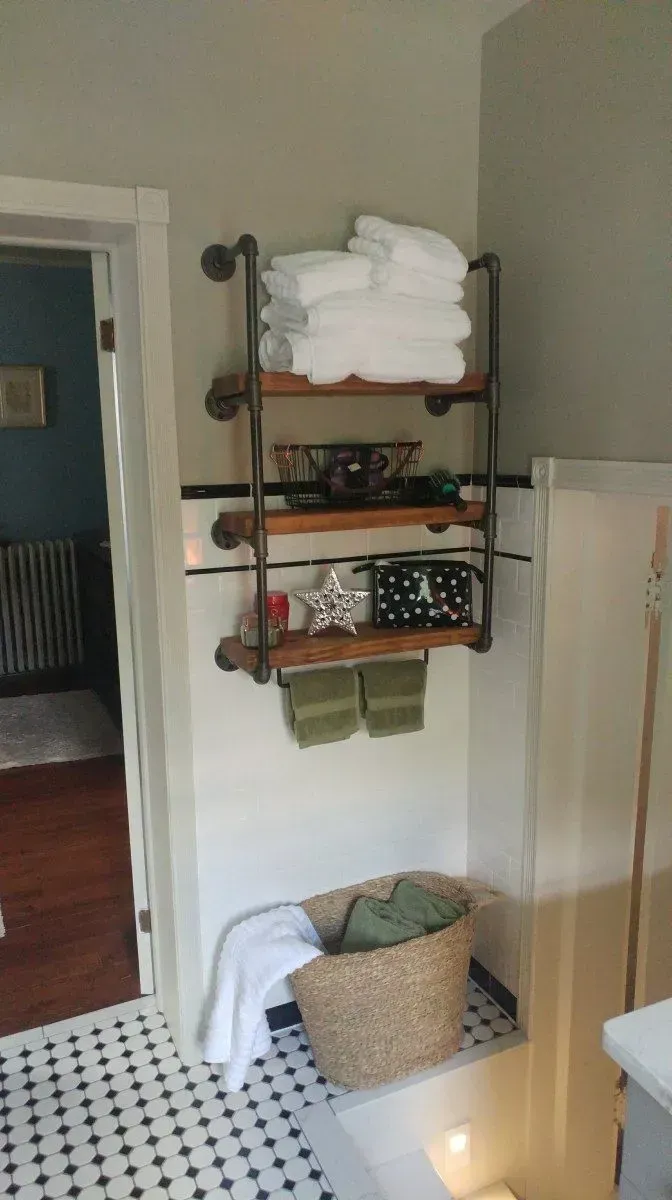 A bathroom with a shelf filled with towels and a basket on the floor.