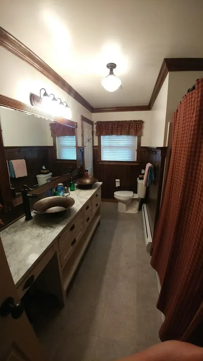 A bathroom with a toilet , sink , mirror and shower curtain.