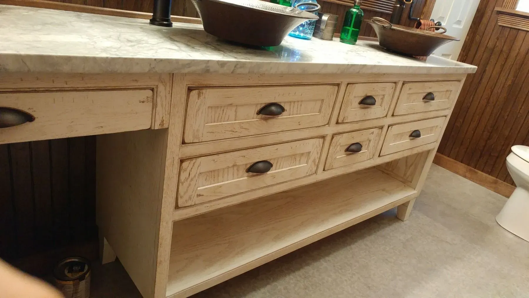 A bathroom vanity with drawers , a sink and a toilet.