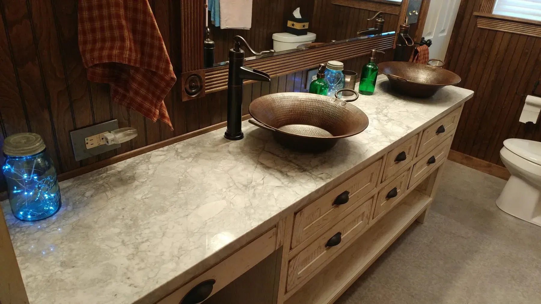 A bathroom with two sinks , a toilet and a mirror.