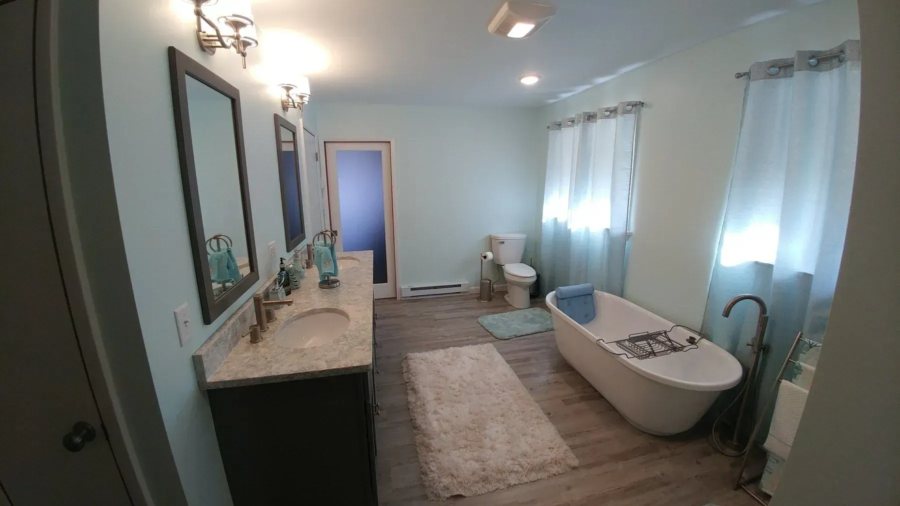 A bathroom with a tub , sink , toilet and mirror.