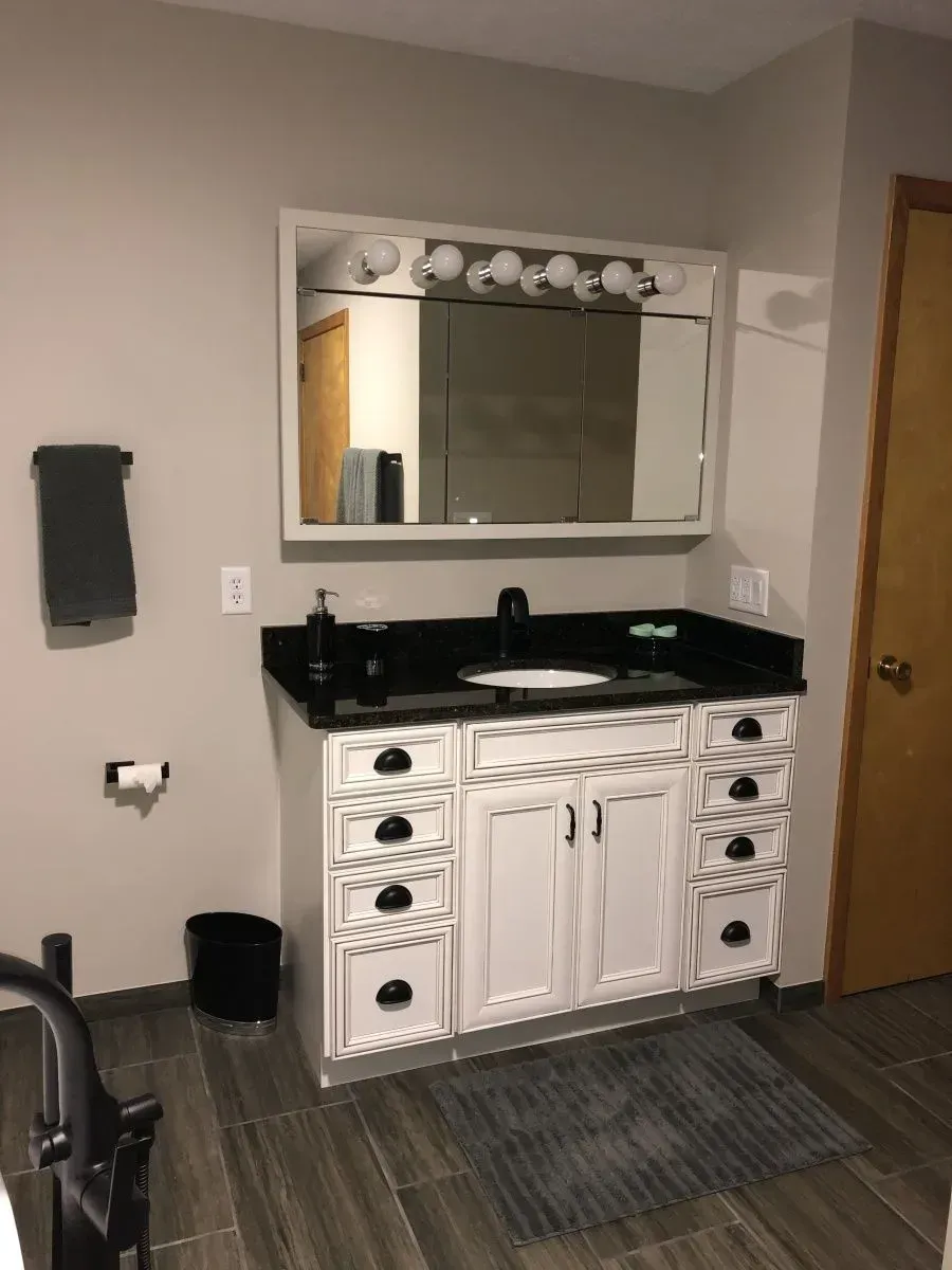 A bathroom with a sink , mirror and cabinets