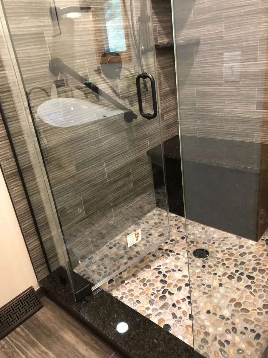 A bathroom with a walk in shower and a sink.