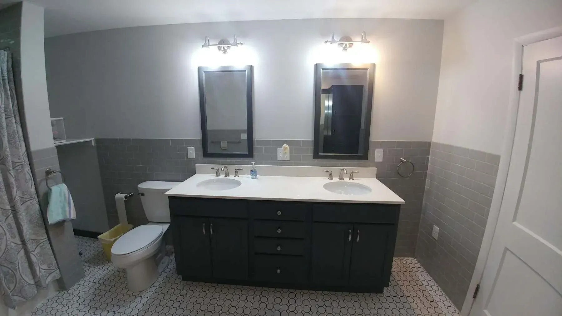 A bathroom with two sinks , a toilet , and two mirrors.