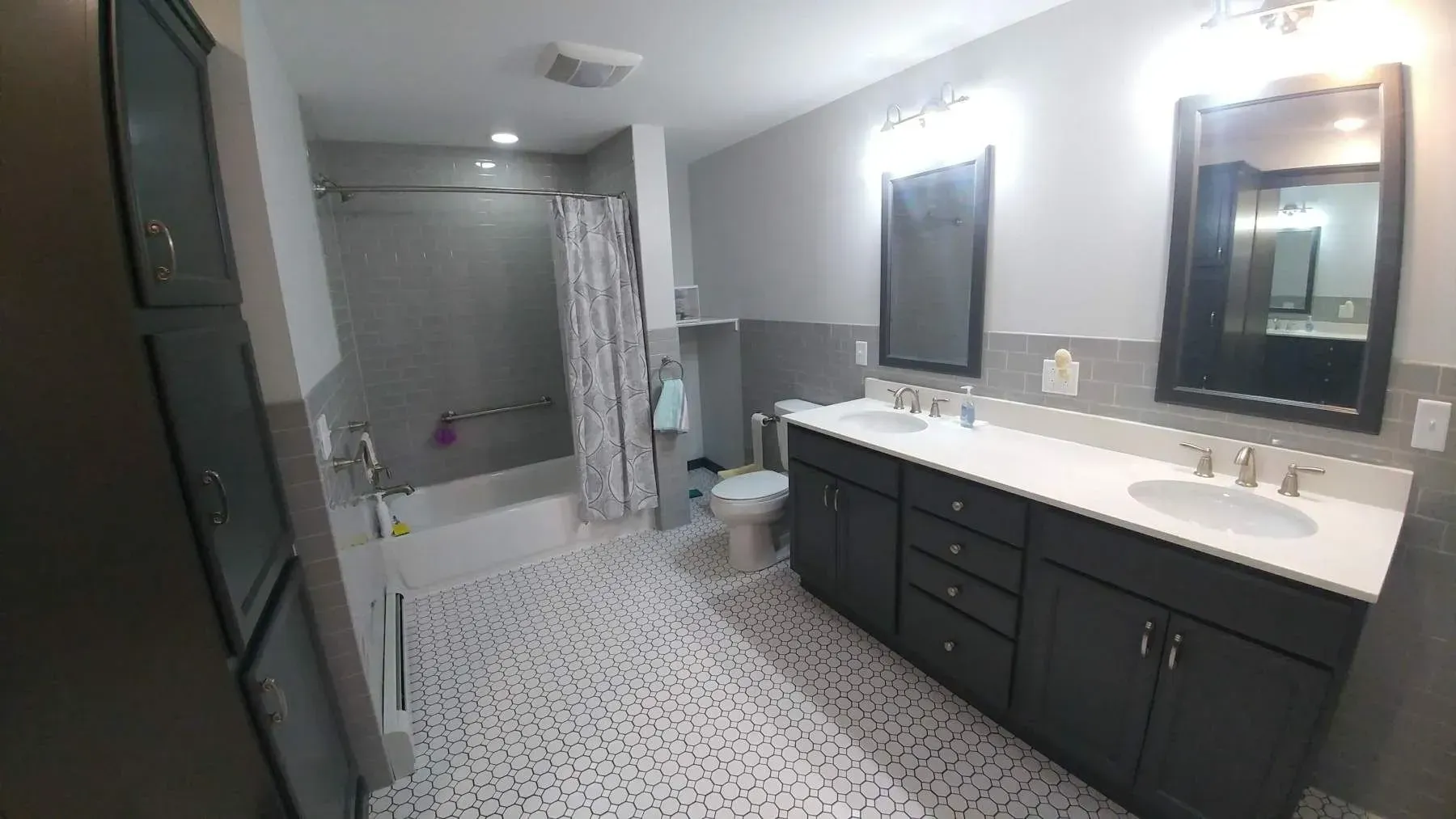 A bathroom with two sinks , a toilet , and a shower.