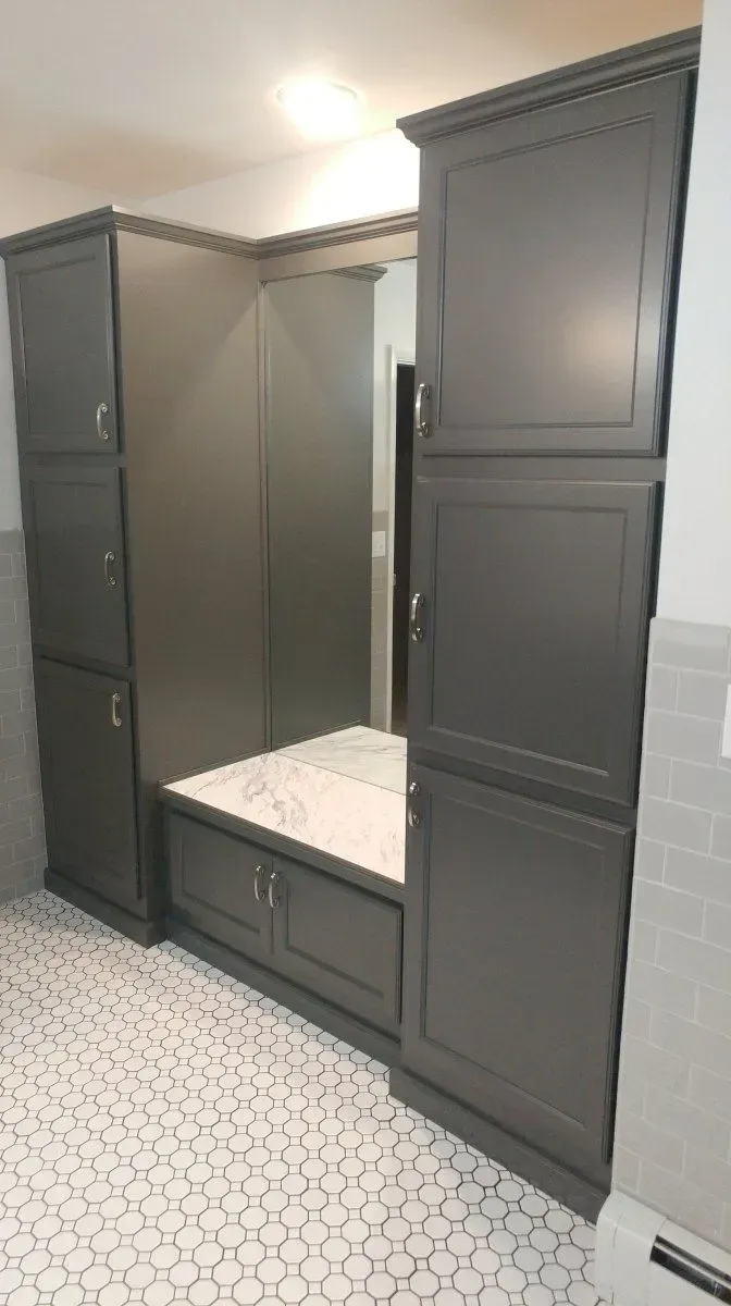 A bathroom with black cabinets and a white tile floor.