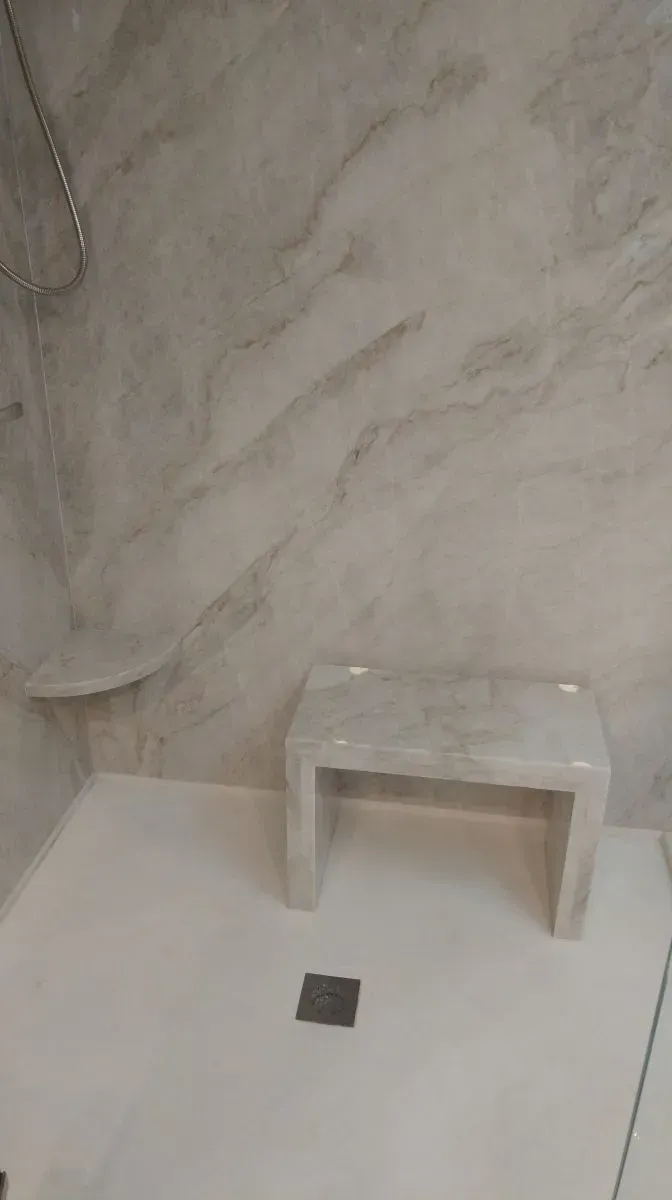 A bathroom with a shower and a bench in it.