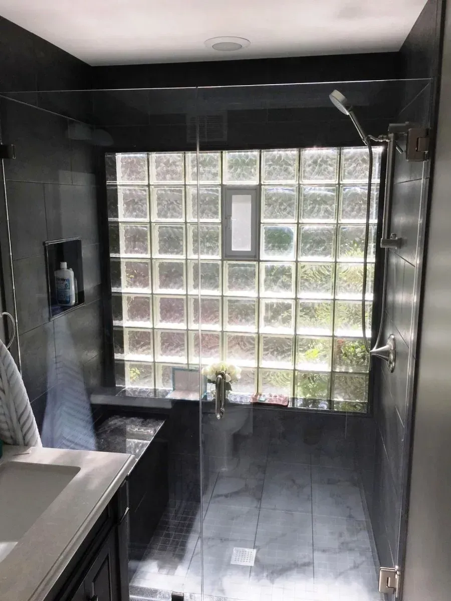A bathroom with a glass shower door and a window.