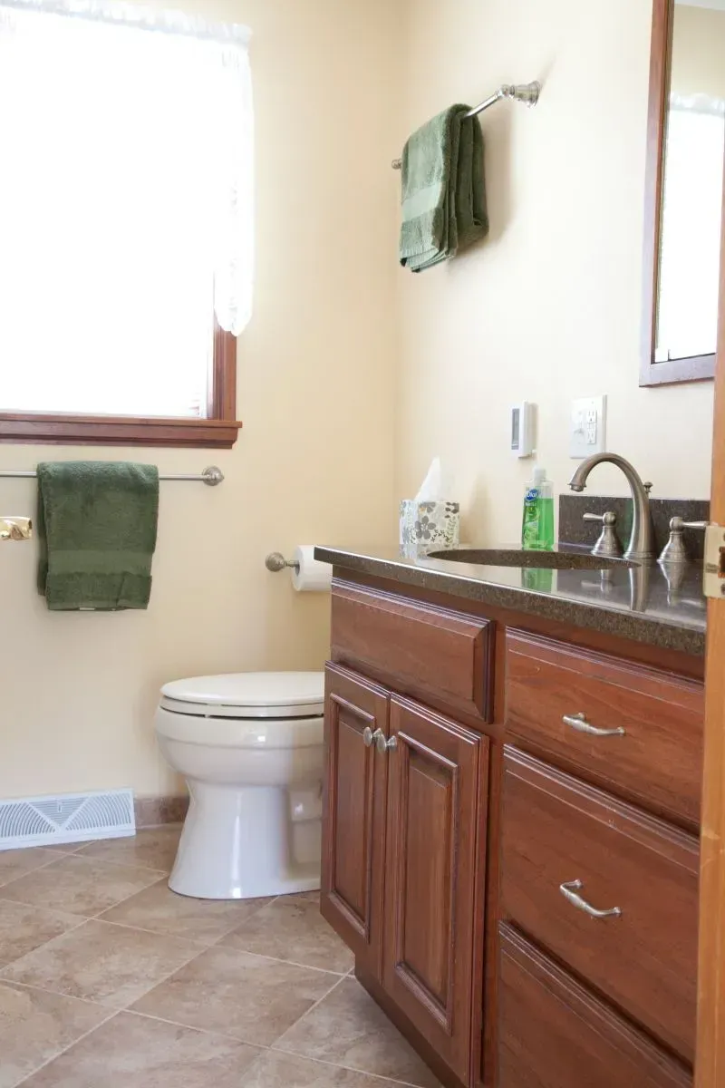 A bathroom with a toilet a sink and a mirror