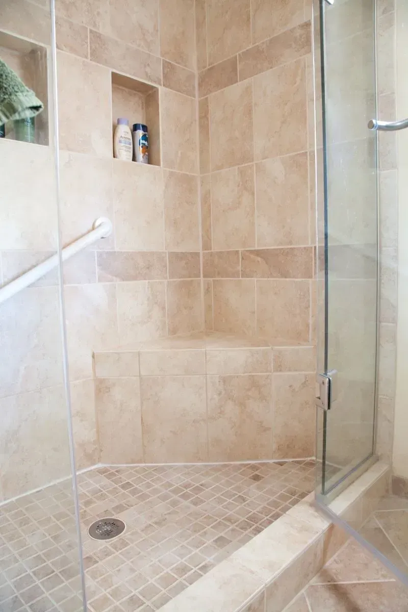 A bathroom with a walk in shower with a glass door
