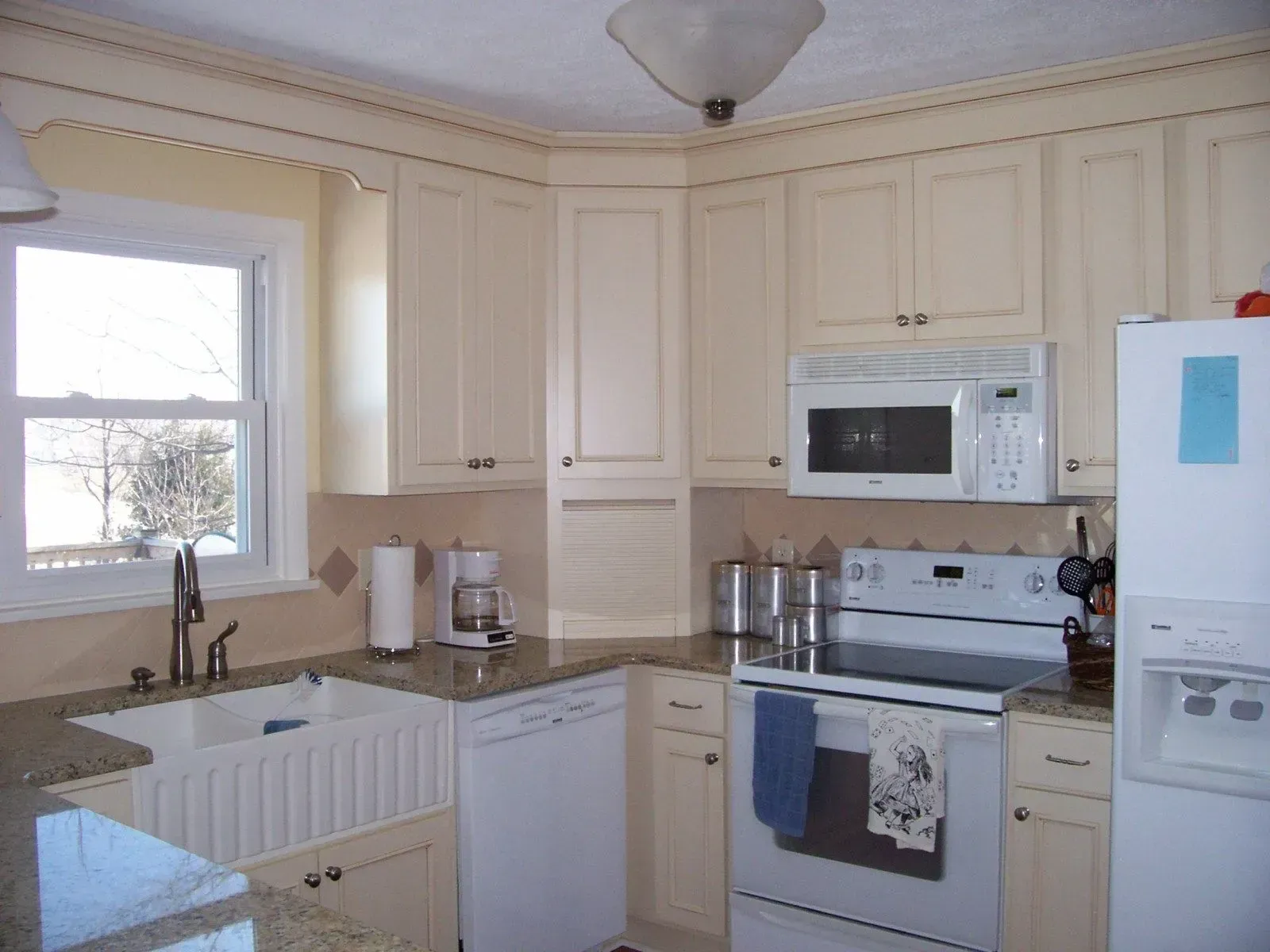 A kitchen with white cabinets a stove a microwave and a sink