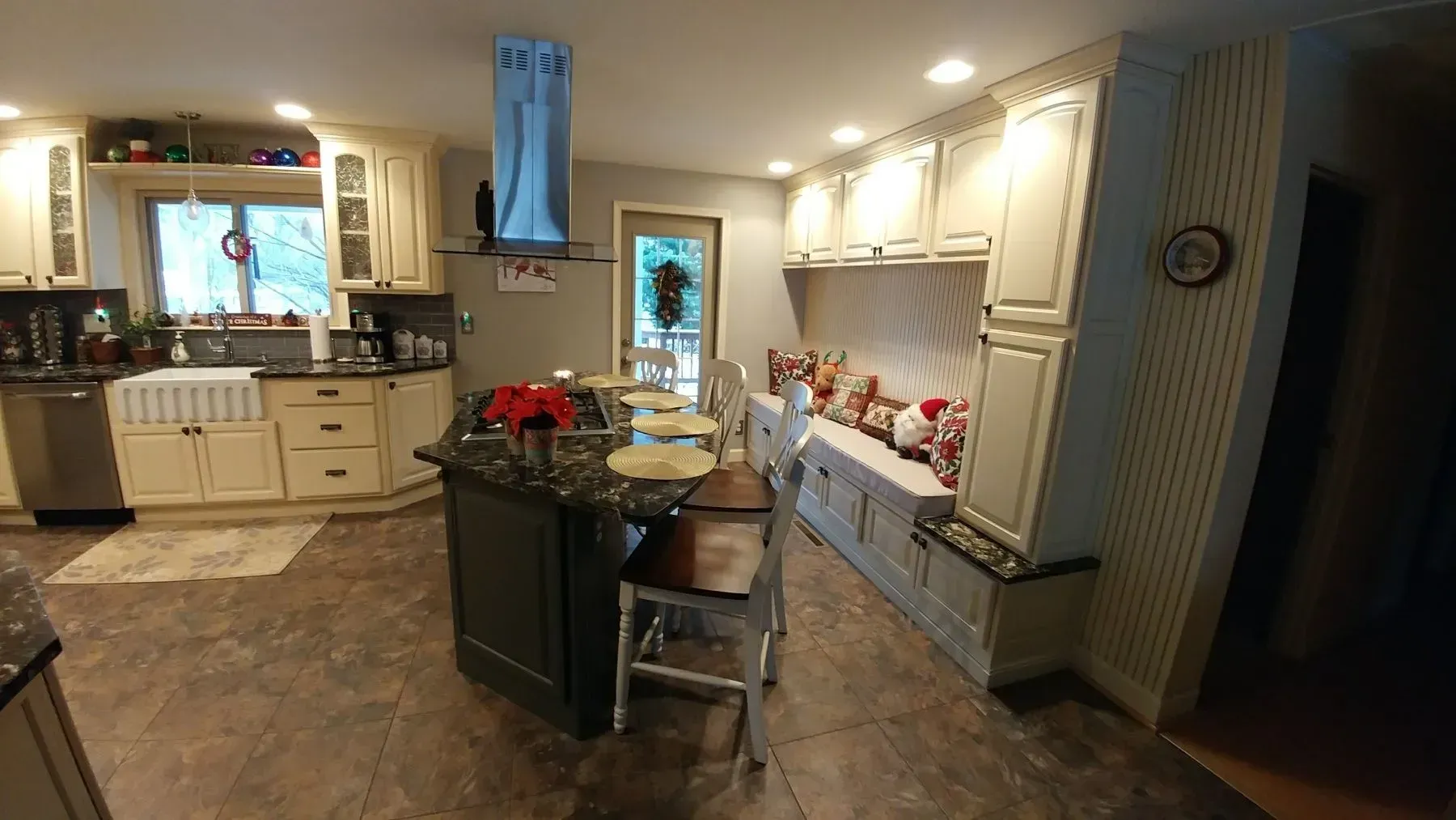 A kitchen with white cabinets , granite counter tops , stainless steel appliances and a large island.