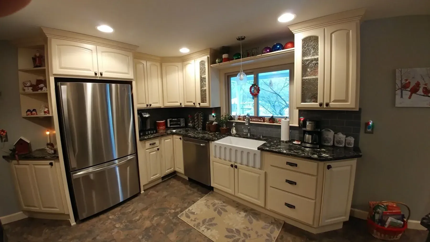 A kitchen with white cabinets , stainless steel appliances , a refrigerator and a sink.