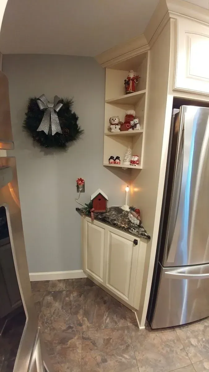 A kitchen with a stainless steel refrigerator and a wreath on the wall.