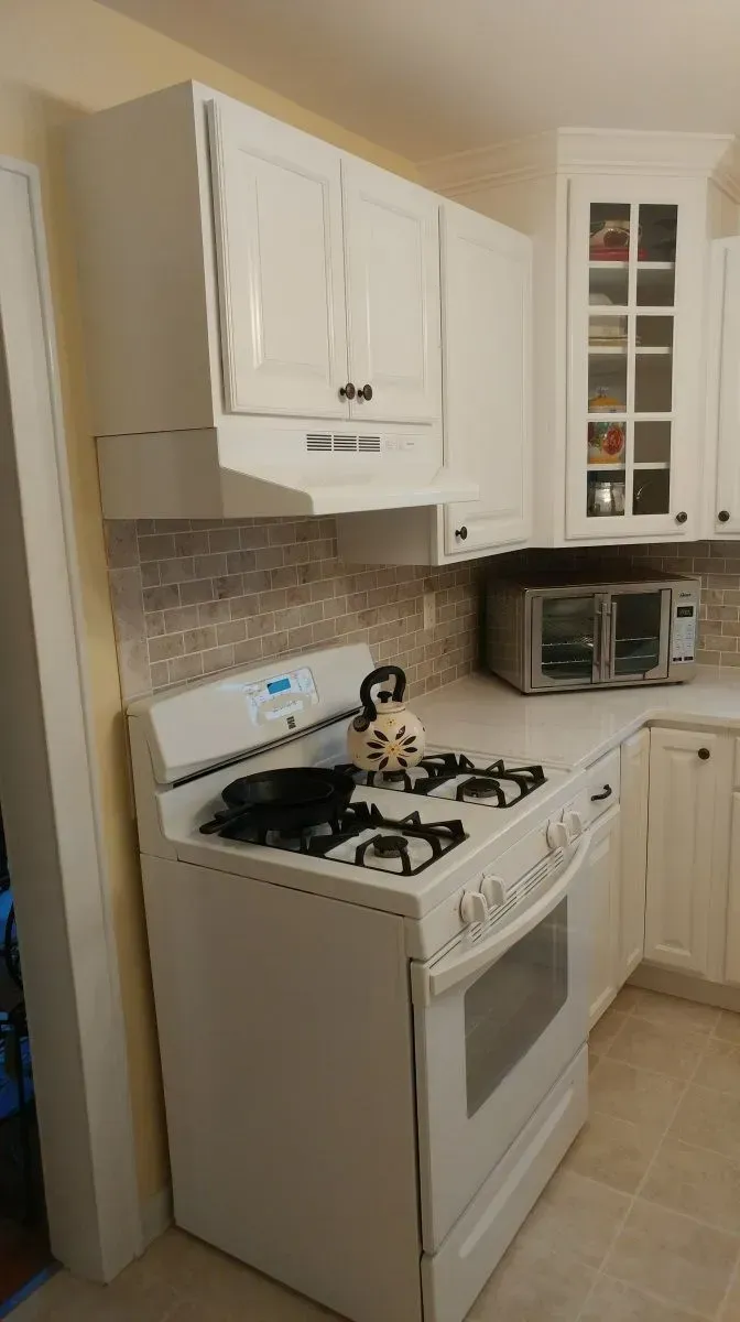 A kitchen with a stove , oven , microwave and cabinets.