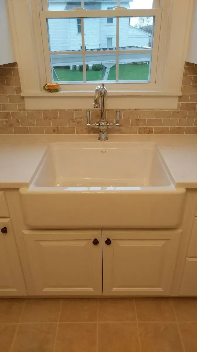 A white kitchen sink with a window in the background.