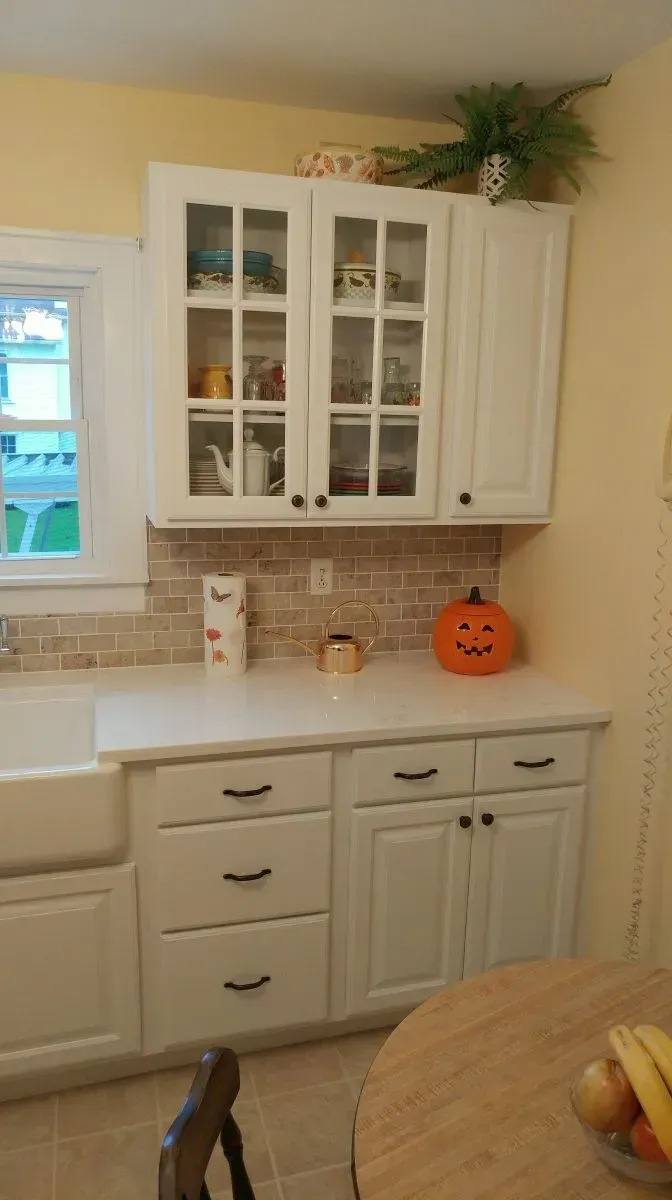 A kitchen with white cabinets and a pumpkin on the counter