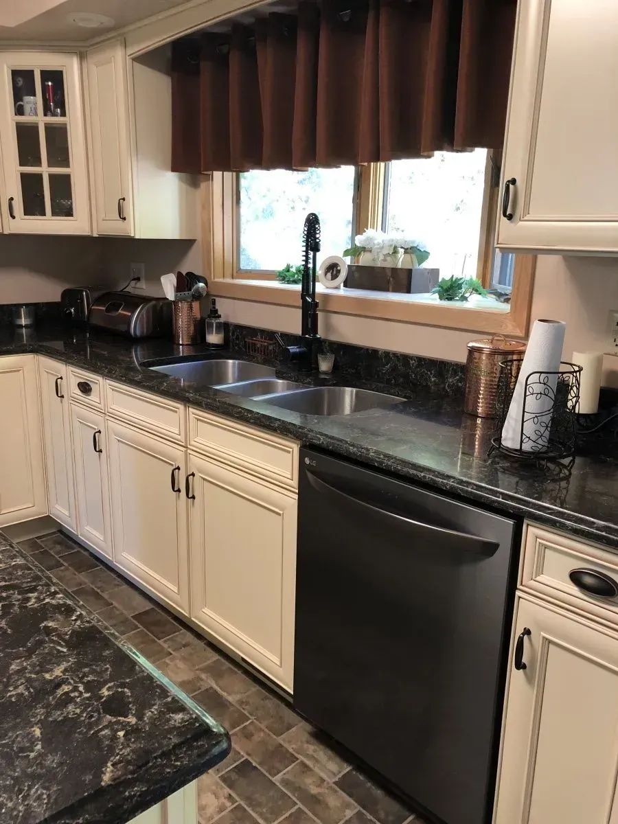 A kitchen with white cabinets and a black dishwasher