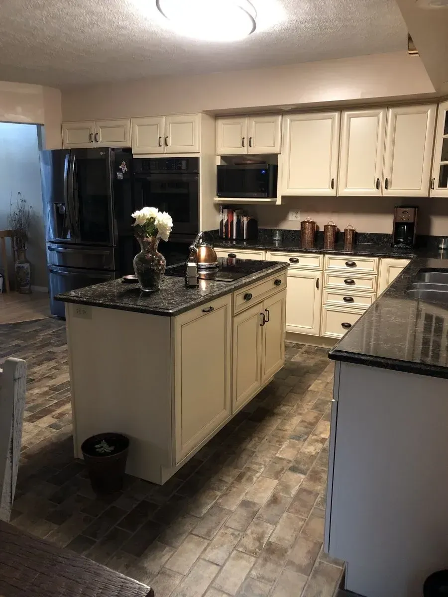A kitchen with white cabinets and black counter tops