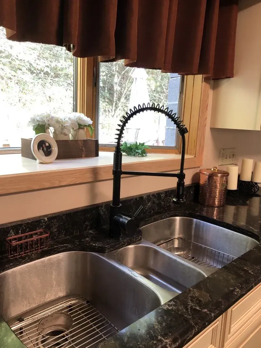 A kitchen sink with a faucet and a window