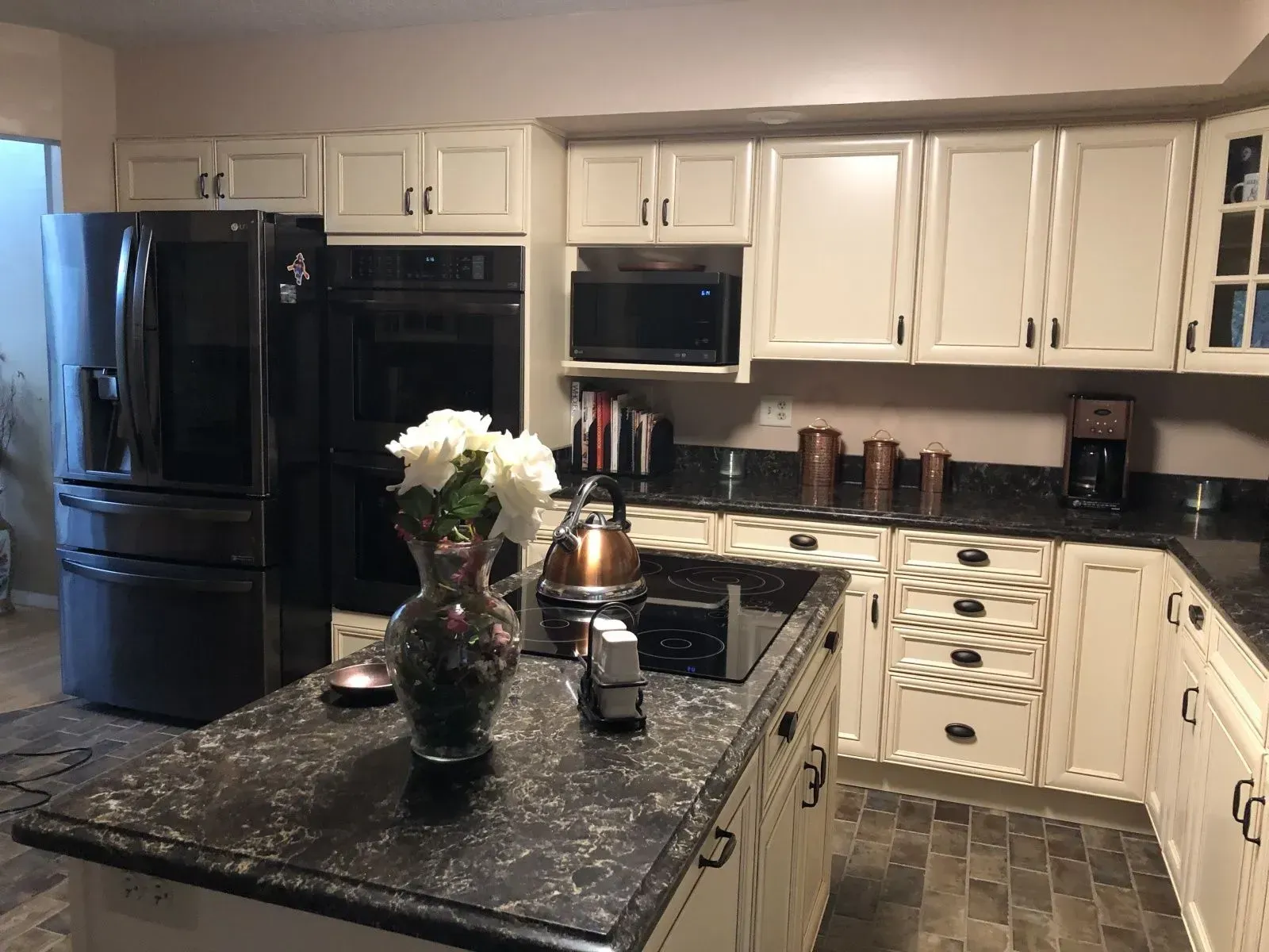 A kitchen with white cabinets and black counter tops