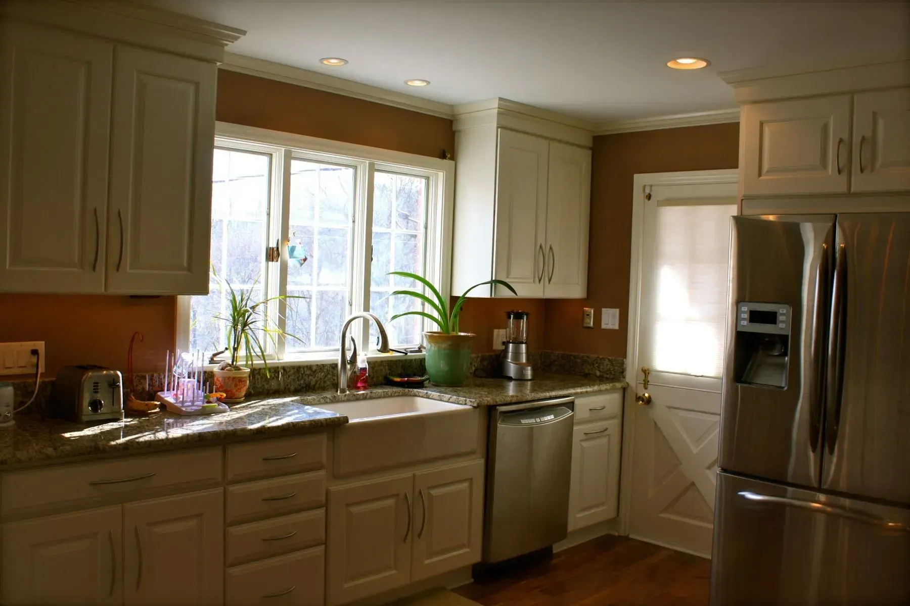 A kitchen with white cabinets and a stainless steel refrigerator