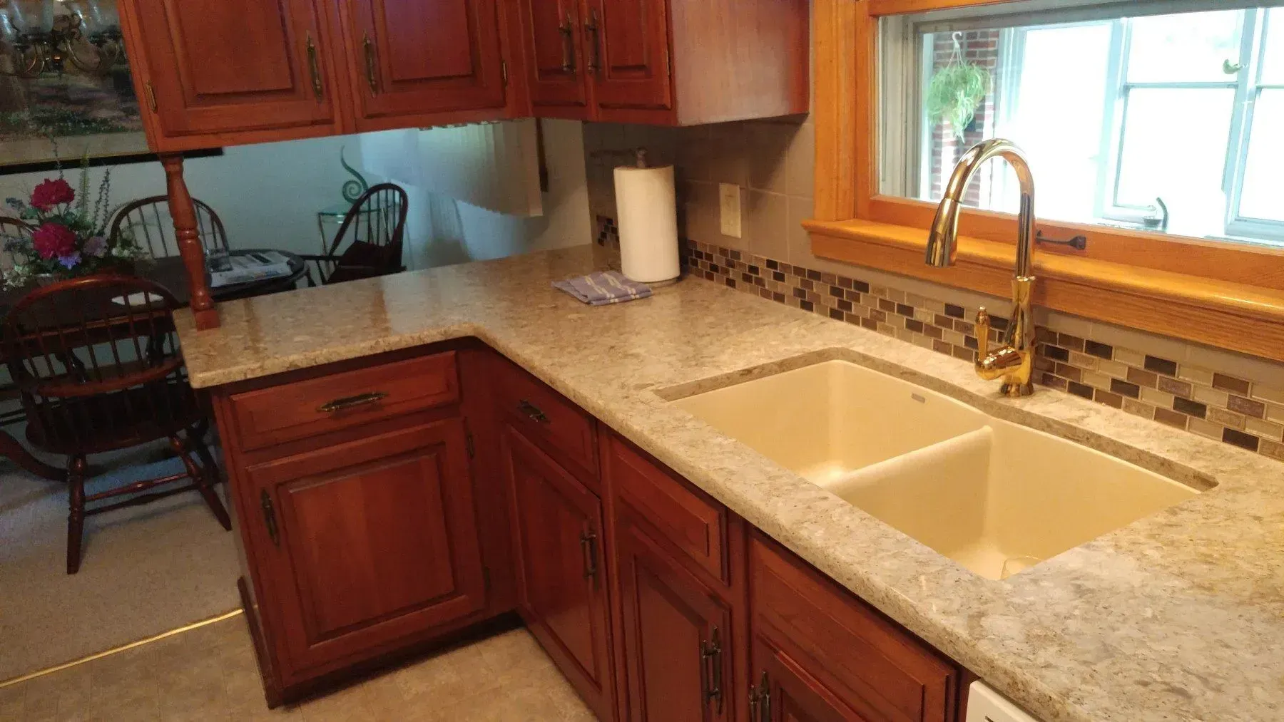 A kitchen with a sink , cabinets , and a window.