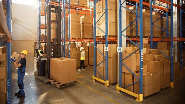 A man is loading boxes into a forklift in a warehouse.